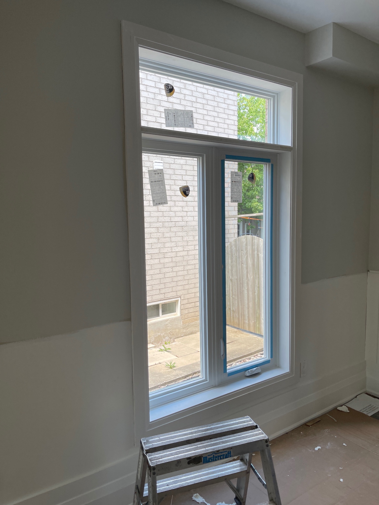 Interior view of the finished combination window — fixed picture pane on top with a fixed casement and operable casement below, framed in stepped wood casing