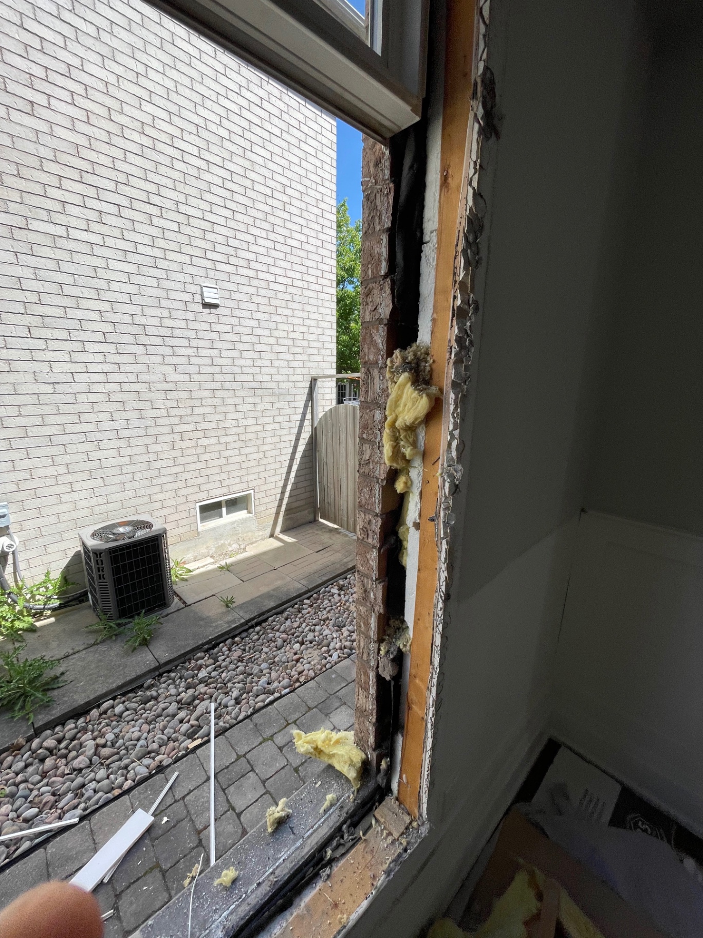 Original window frame removed, showing the exterior frame-to-stud gap with loose fibreglass and no proper insulation present