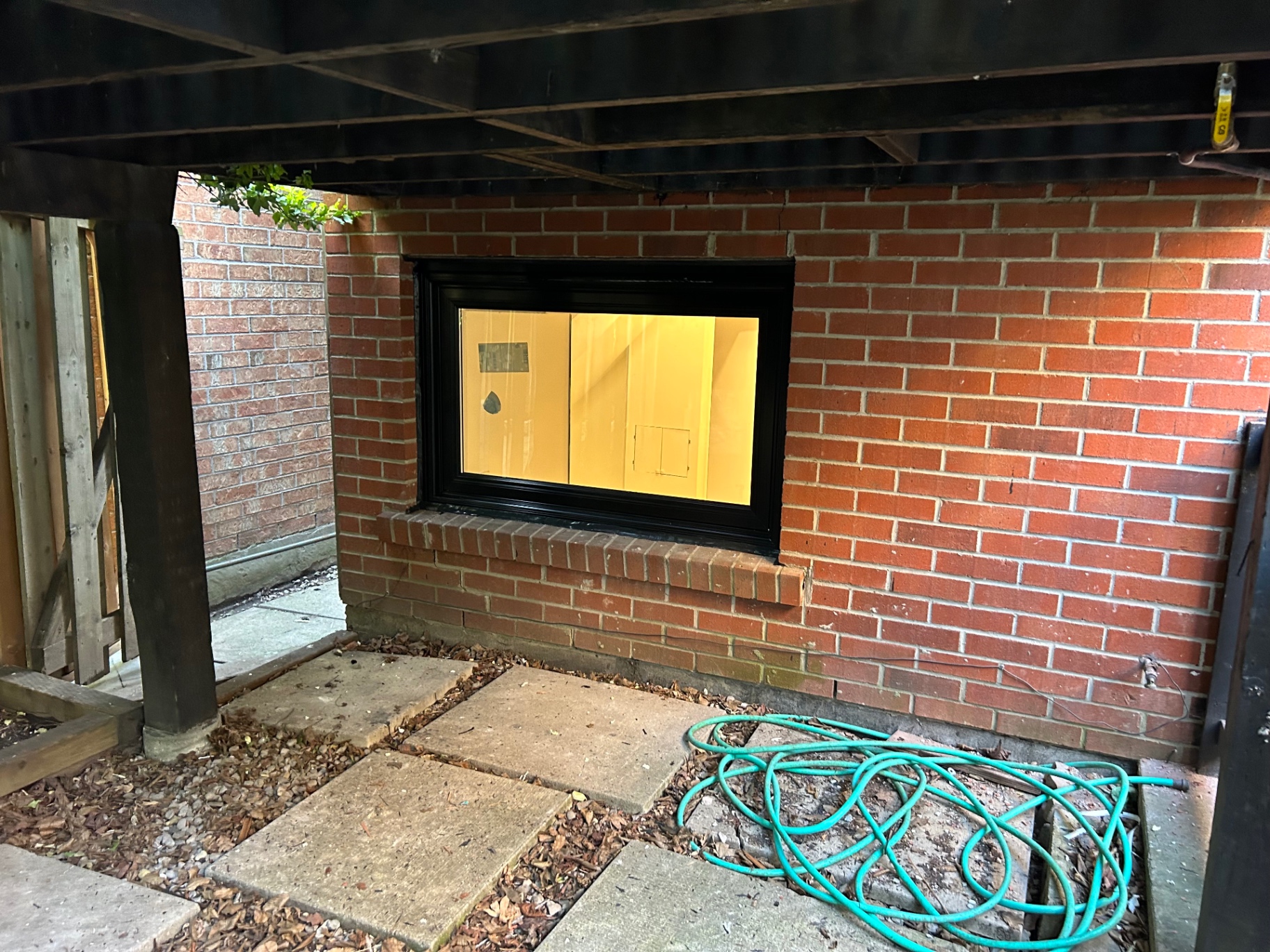 Finished black vinyl basement slider window with galvanized window well in Vaughan