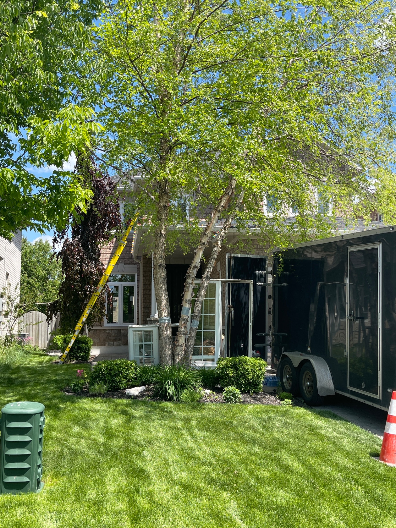 Front of the Richmond Hill home during installation, with a ladder against the wall and window units staged on the walkway beside the crew trailer