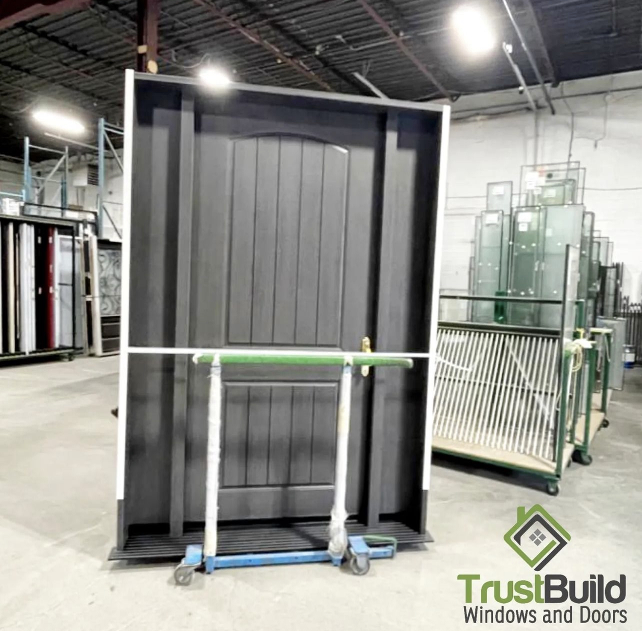 Custom black fiberglass entry door unit with sidelights staged in the Trust Build warehouse before installation
