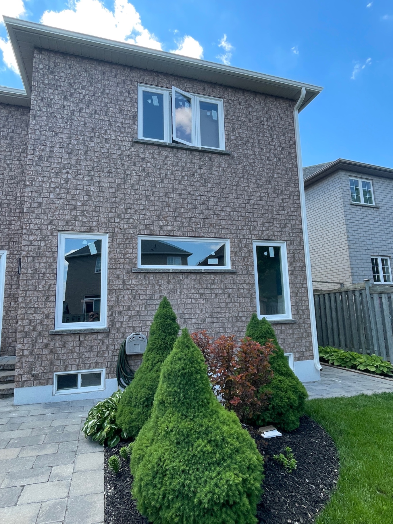 Rear elevation of a Richmond Hill brick home after a full-frame energy-efficient window rebuild, with new white casement, awning and fixed windows installed
