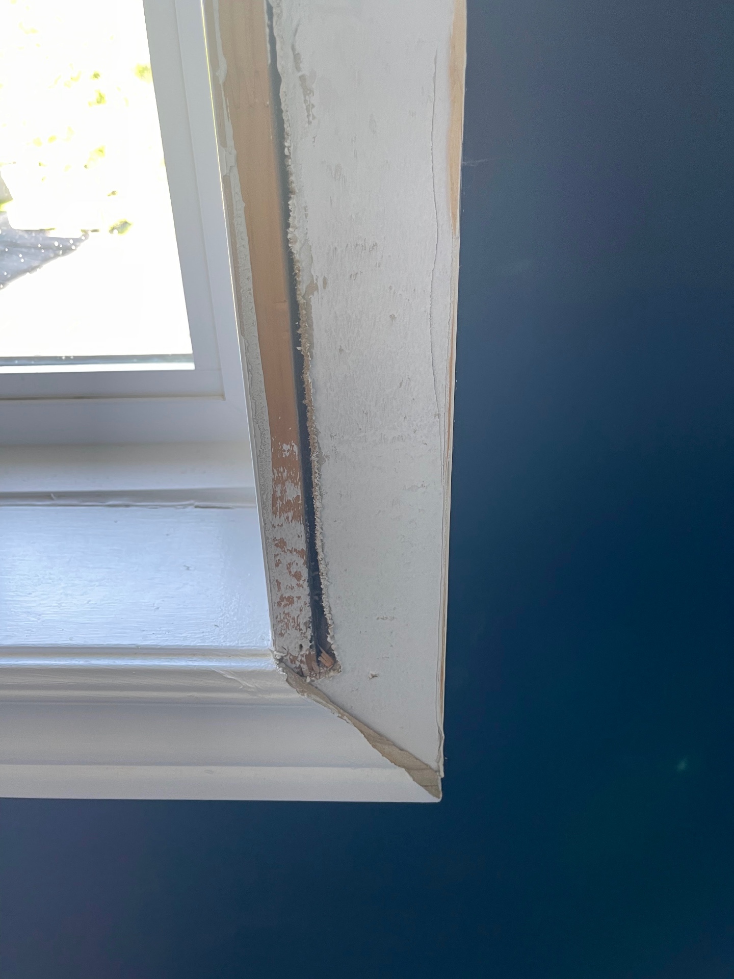Close-up of the original interior casing pulled away, showing an empty uninsulated void between the exterior window frame and the stud