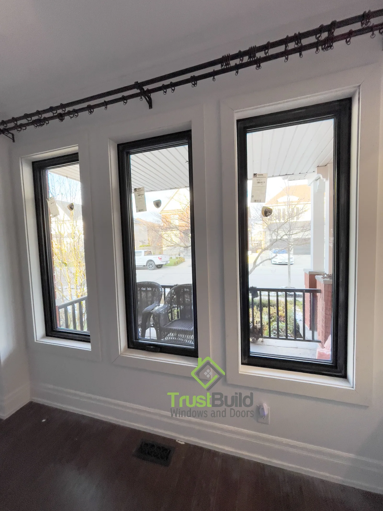 Three tall black-framed windows with white interior casing overlooking a balcony in a Pickering living room