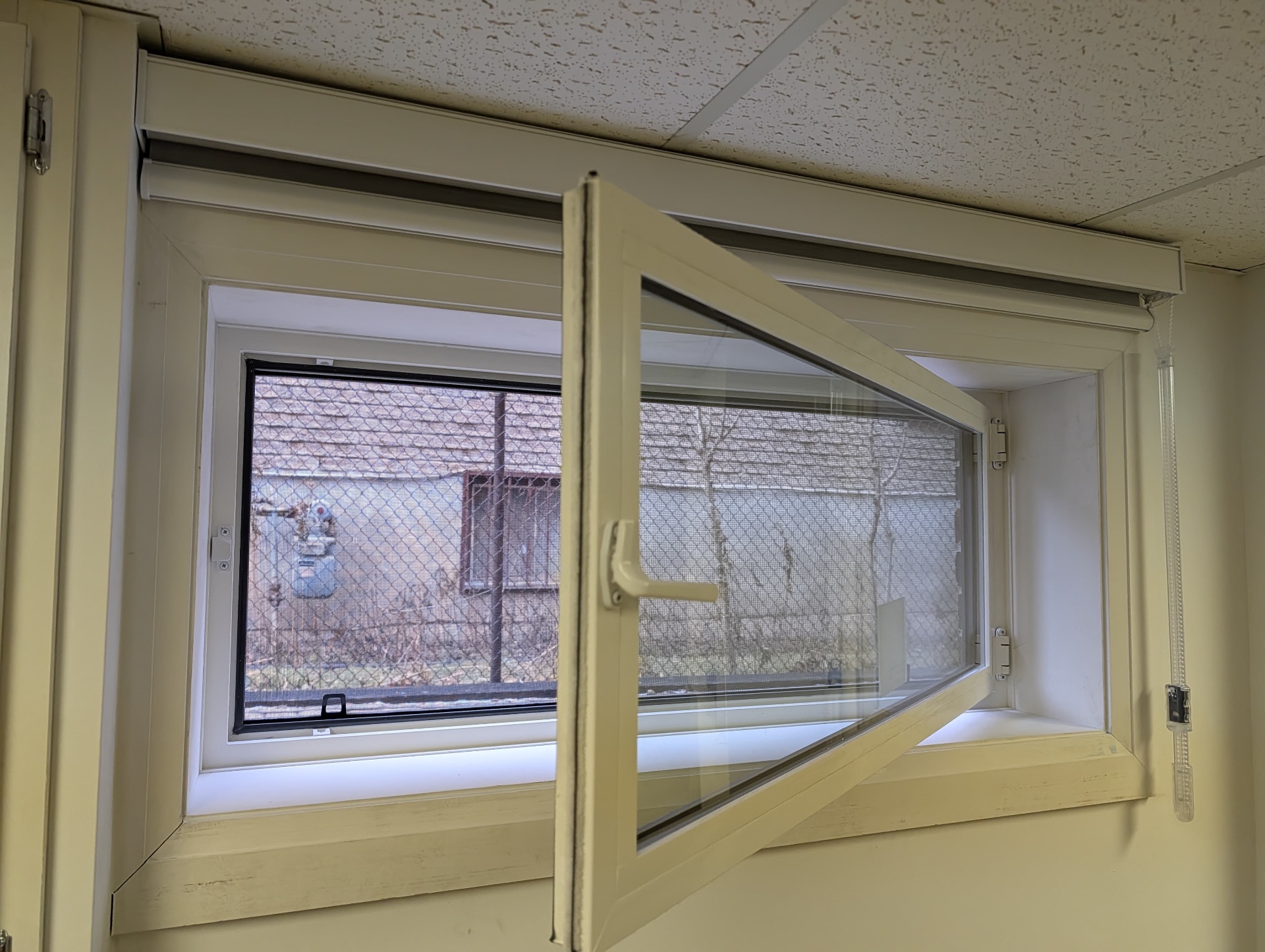 Tilt-and-turn window open inward with finished interior trim and a roller blind mounted above