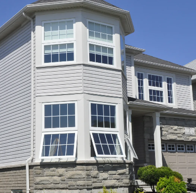 White awning windows stacked in a two-storey bay tower with stone base on an Ontario home by Trust Build