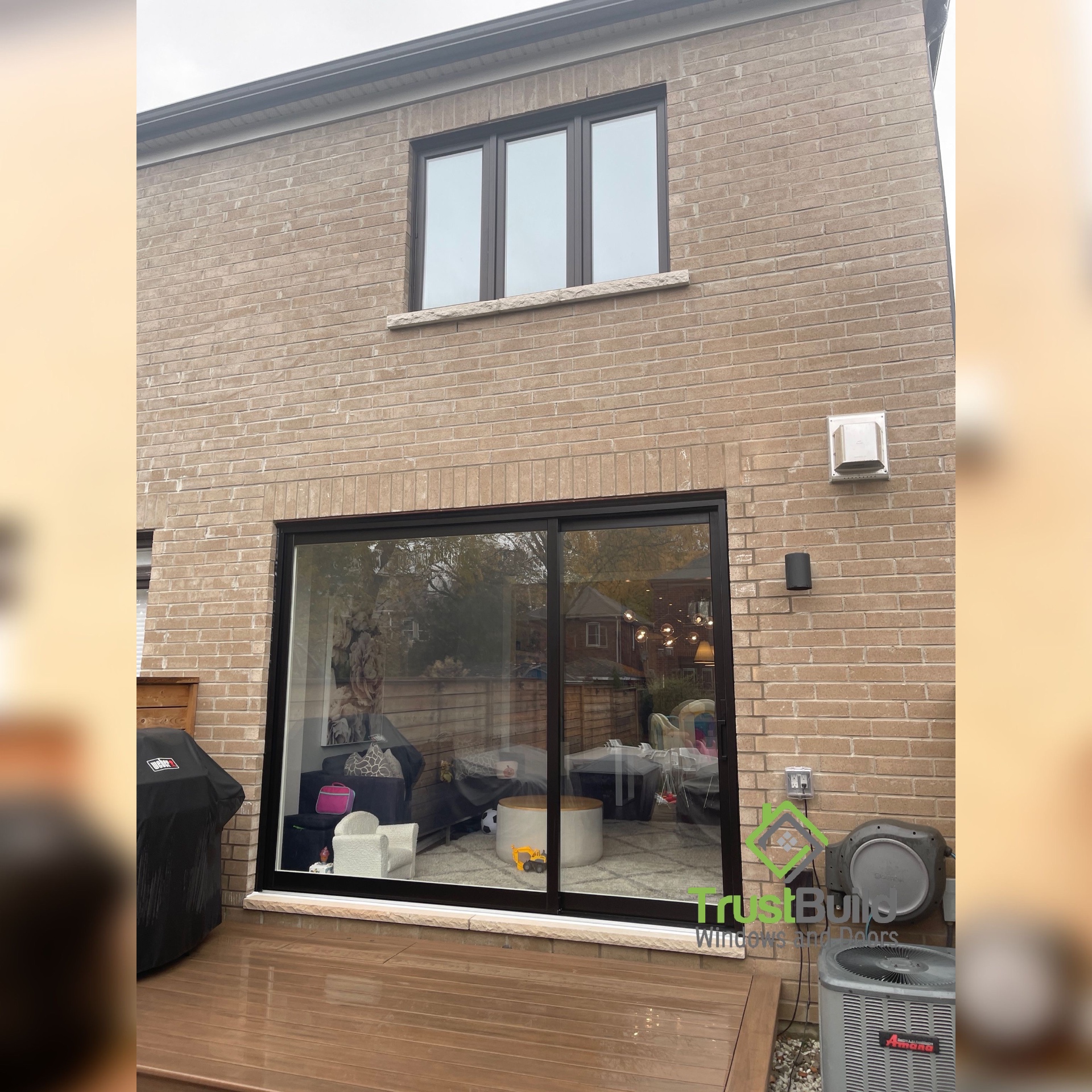 Black replacement windows and sliding patio door on the rear of a two-storey brick home