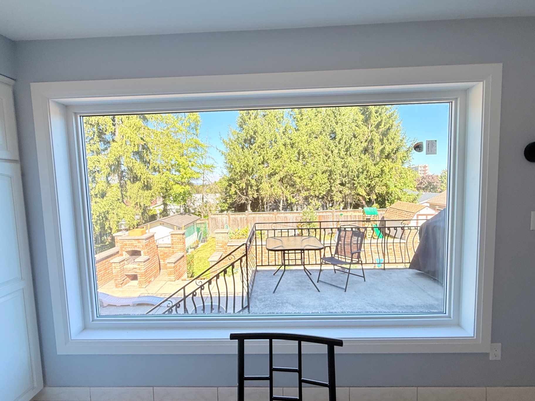 Large fixed picture window with a clear backyard view from inside an Ontario home
