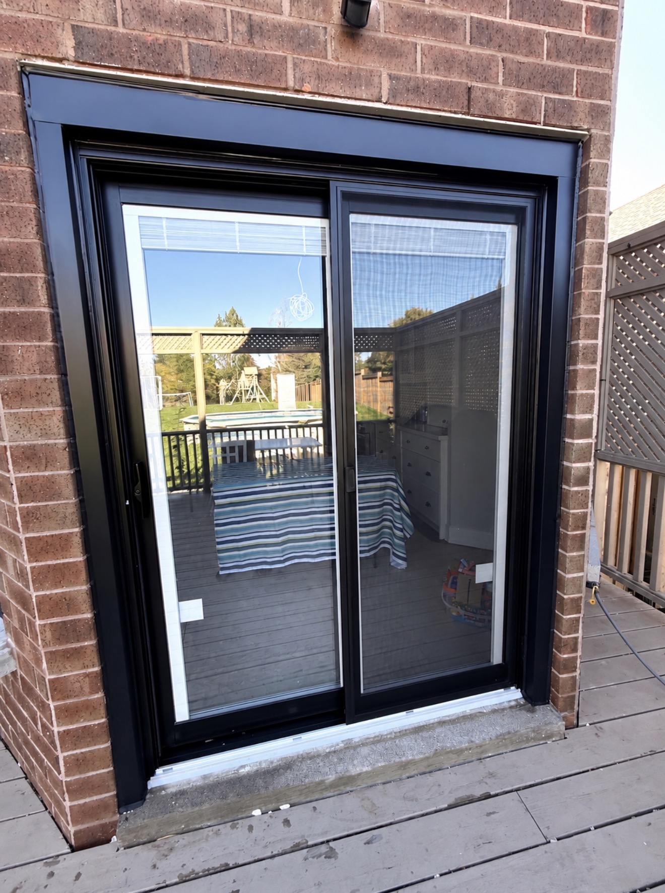 Exterior view of the new black sliding patio door in Cobourg, brick-to-brick installation, reinforced aluminum frame