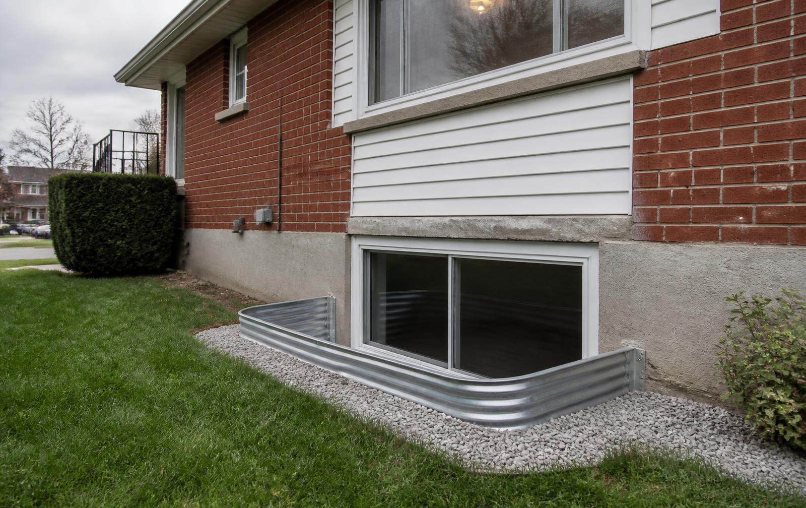 Newly installed basement egress window with a galvanized window well on a postwar Oshawa brick bungalow