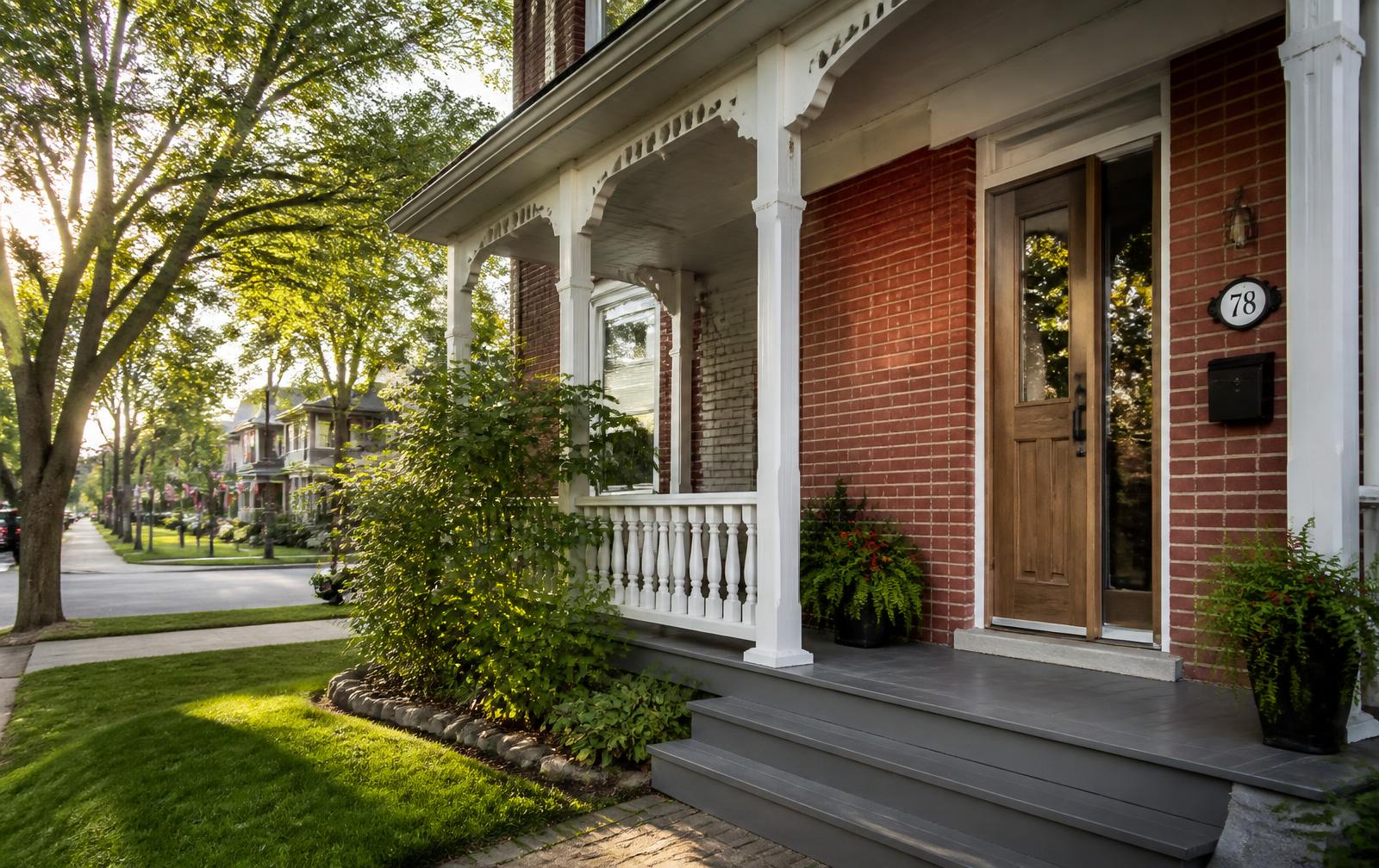 Stained woodgrain fiberglass entry door with a sidelight on a red brick century home on a tree-lined St. Thomas street
